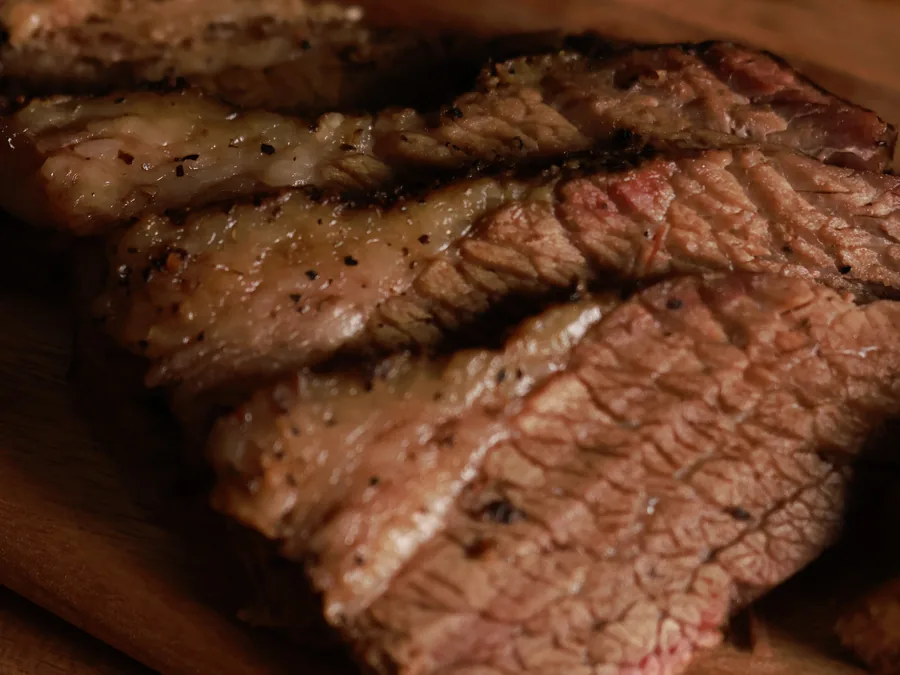 12-hour smoked Angus brisket sliced across the grain on a wooden board