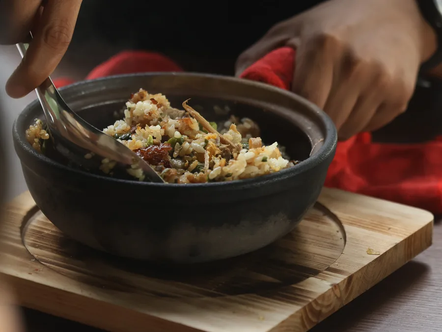 Angmo claypot rice served in a black claypot on a wooden board