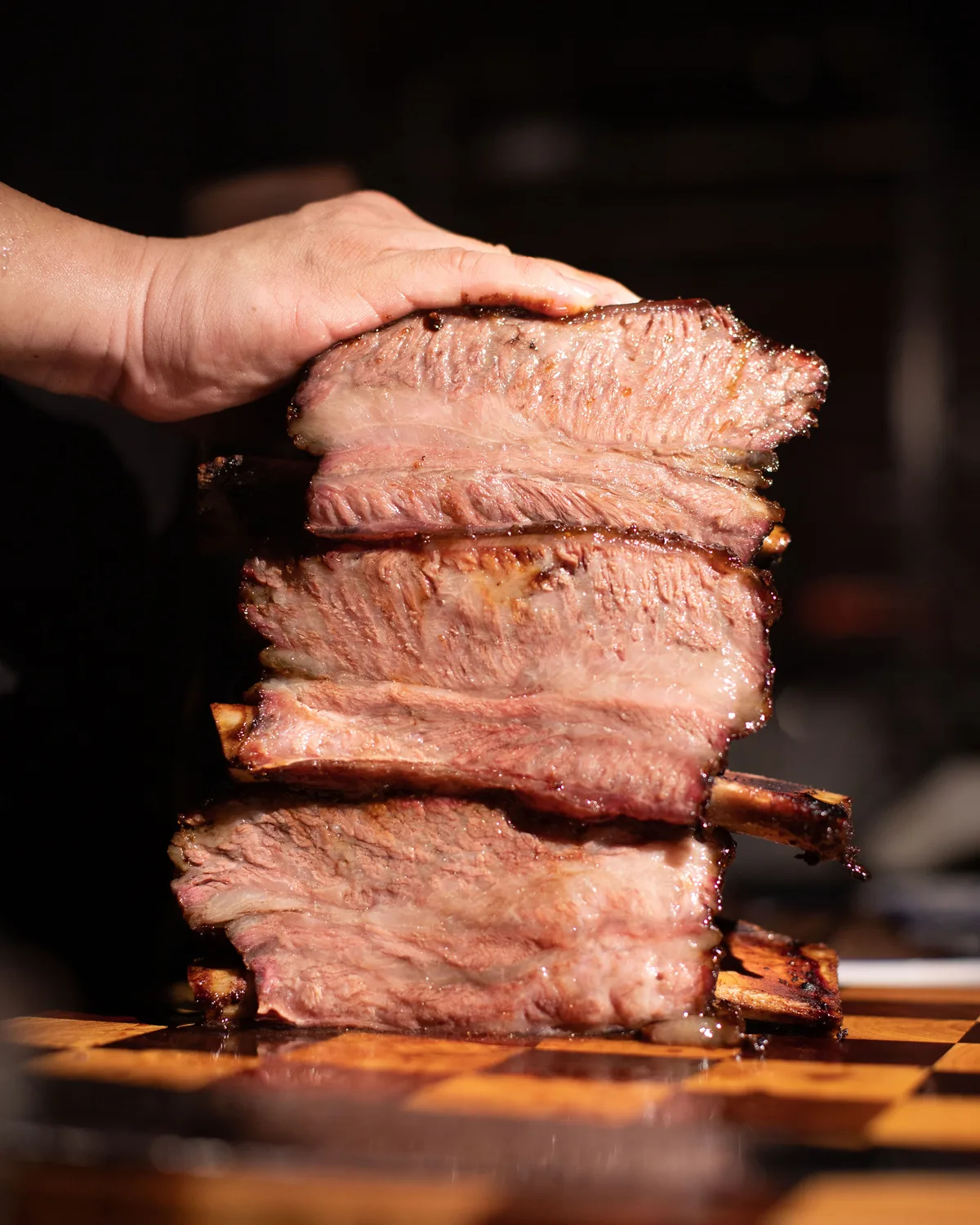 A stack of thick mangrove-smoked ribs lifted from the board